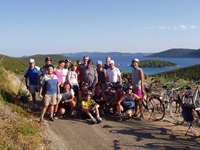 Eine Radlergruppe posiert vor einer idyllischen Bucht für ein Foto.