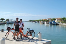 Ein Radlerpärchen posiert in einem italienischen Hafen für ein Foto.