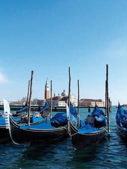 Die berühmten Gondeln Venedigs schaukeln im Wasser, im Hintergrund der Campanile und die Kirche von San Giorgio Maggiore.