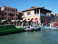 Ein Wassertaxi und Boote vor einem Palazzo in Venedig.