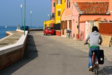 Eine Radlerin vor den bunten Häusern von Pellestrina.