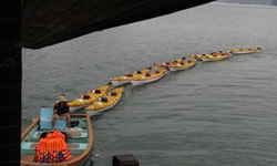 Eine vietnamesische Dschunke zieht Boote hinter sich her