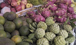 Eine vietnamesische Frau verkauft an einem Marktstand Obst und Gemüse.