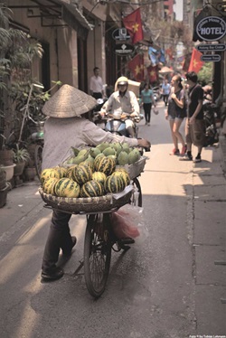 Ein vietnamesischer Bauer transportiert auf seinem Fahrrad Früchte durch die Straßen von Hanoi.