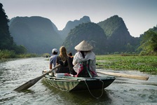 Teilnehmer einer Inselhüpfen-Reise fahren mit dem Ruderboot in ein verstecktes Tal bei Tam Coc in Vietnam.