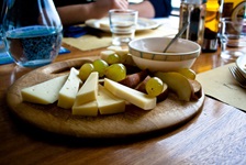 Holzbrett mit Käse, Trauben und Wurst.