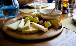 Holzbrett mit Käse, Trauben und Wurst.