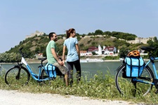 Ein Radlerpärchen macht bei den Burganlagen von Devin eine Pause am Donauufer.