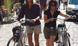 Zwei Radlerinnnen schieben ihre Räder durch ein Dorf im Elsass
