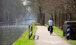 Radfahrer fährt auf einem Radweg neben einem Fluss im Elsass entlang