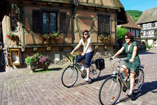 Zwei Radlerinnen fahren durch ein typich elsässisches Dorf