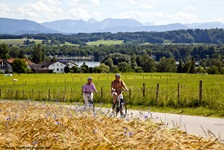 Zwei Radfahrer vor der wunderschönen Kulisse des von Bergen überragten Waginger Sees.