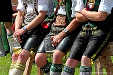 Traditionelle bayerische Gemütlichkeit, wie sie im Buche steht: In Tracht und Lederhose gekleidete Burschen machen Pause und halten ihre Bierkrüge in der Hand.