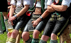 Traditionelle bayerische Gemütlichkeit, wie sie im Buche steht: In Tracht und Lederhose gekleidete Burschen machen Pause und halten ihre Bierkrüge in der Hand.