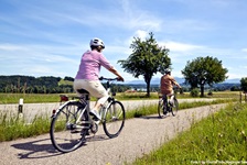 Zwei Radfahrer radeln auf den schönen Waginger See zu.