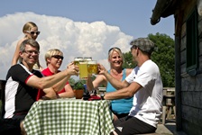 Eine Radlergruppe prostet sich vor einer Hütte mit einem erfrischenden Bier zu.