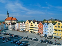 Die Silberzeile in der Barockstadt Schärding ist bekannt für ihre bunten Häuserfassaden. Dahinter erhebt sich die Stadtpfarrkirche des hl. Georg.