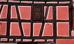Blick auf eine typische Fachwerkhausfassade im Elsass, die lachsfarben gestrichen ist.