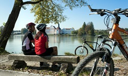 Ein Radfahrerpärchen macht auf einer Bank am Innufer Pause.