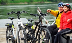 Zwei Radler sitzen auf einer Bank auf einem Steg an der Donau