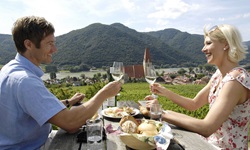 Ein Paar macht in Weißenkirchen eine Weinprobe im Freien auf einem nett gedeckten Holztisch