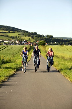 Drei Radler auf dem von reifenden Kornfeldern flankierten Weser-Radweg.