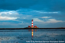 Blick über das Wattenmeer bei Westerhever zum rot-weißen Leuchtturm