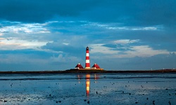 Blick über das Wattenmeer bei Westerhever zum rot-weißen Leuchtturm