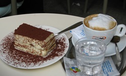 Ein Stück Sahnetorte, ein Glas Wasser und eine Wiener Kaffeespezialität laden in einem Wiener Kaffeehaus zur Stärkung ein.