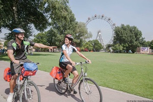 Ein Radlerpaar auf dem Donau-Radweg fährt in Wien beim Riesenrad vorbei