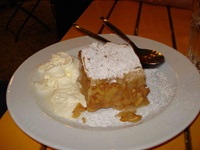 Ein Stück Wiener Apfelstrudel mit Sahne auf einem Teller.