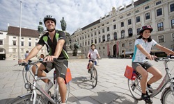 Drei Radler vor der Wiener Hofburg.