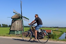 Ein Radler fährt an einer Windmühle vorbei.