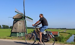Ein Radler fährt an einer Windmühle vorbei.