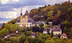 Die auf dem Nikolausberg gelegene Wallfahrtskirche Käppele in Würzburg wird idyllisch von Wald umrahmt.