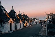 Trulli-Häuser von Alberobelle in Süditalien, deren weiße Wände und kegelförmige Dächer vor einem pastellfarbenen Abendhimmel leuchten